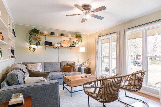 living room featuring a textured ceiling, light wood-style floors, and a ceiling fan