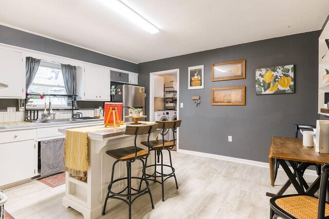 kitchen featuring washer and dryer, open shelves, white cabinets, and freestanding refrigerator