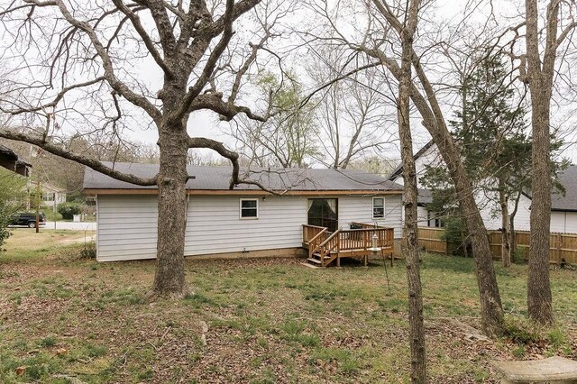 rear view of property featuring a lawn, a deck, and fence
