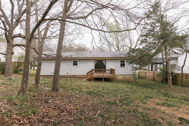 back of property featuring a lawn, a wooden deck, and fence