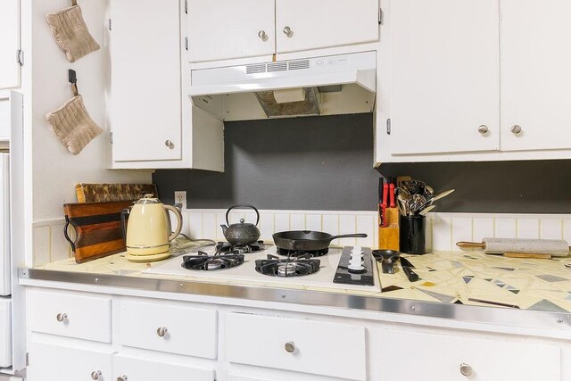 kitchen featuring light countertops, under cabinet range hood, and white cabinets