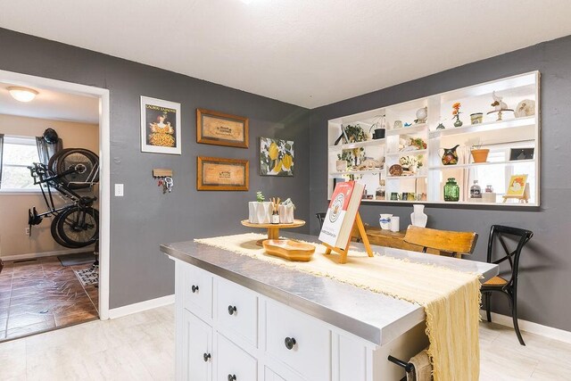 kitchen featuring baseboards, white cabinets, and open shelves