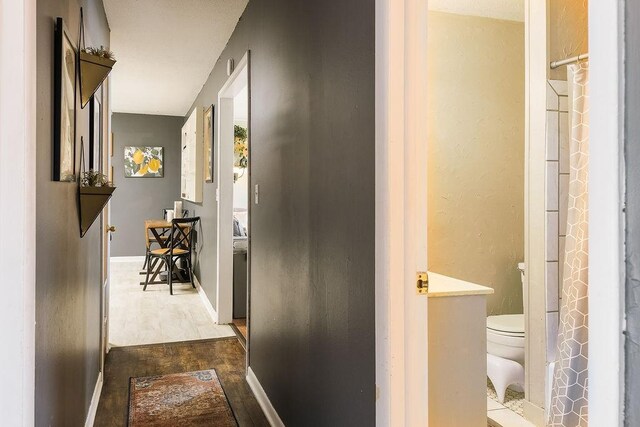 corridor featuring baseboards and dark wood finished floors
