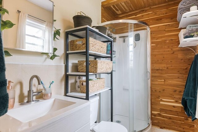 bathroom featuring wood walls, toilet, vanity, a stall shower, and wood ceiling