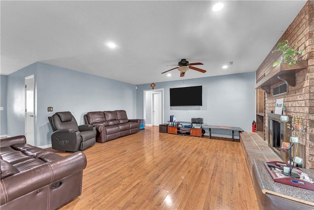 living room featuring recessed lighting, baseboards, light wood finished floors, ceiling fan, and a brick fireplace
