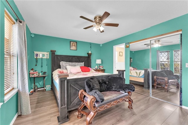 bedroom featuring baseboards, a closet, wood finished floors, and a ceiling fan