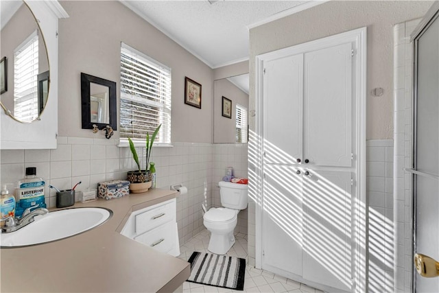 full bath with tile patterned floors, toilet, tile walls, and a healthy amount of sunlight