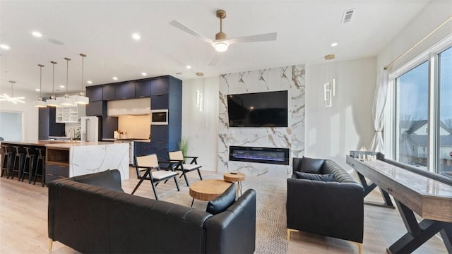225 SE 7th St, Bentonville, AR 72712 - living room featuring light wood finished floors, a high end fireplace, a ceiling fan, and recessed lighting