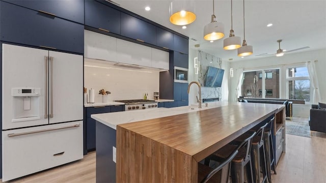 225 SE 7th St, Bentonville, AR 72712 - kitchen with high end fridge, light wood-style flooring, stainless steel gas cooktop, hanging light fixtures, and light countertops