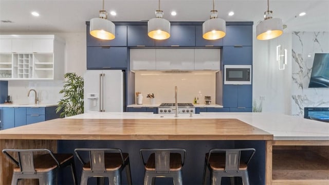 225 SE 7th St, Bentonville, AR 72712 - kitchen featuring white refrigerator with ice dispenser, built in microwave, butcher block countertops, decorative light fixtures, and blue cabinetry