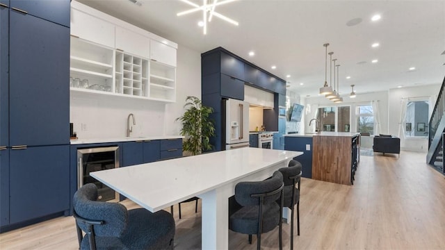 225 SE 7th St, Bentonville, AR 72712 - kitchen featuring white refrigerator with ice dispenser, modern cabinets, a center island with sink, light wood-type flooring, and recessed lighting