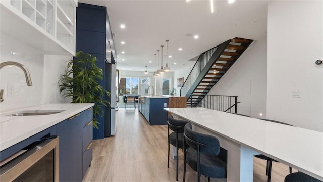 225 SE 7th St, Bentonville, AR 72712 - kitchen featuring wine cooler, blue cabinets, light wood-style floors, modern cabinets, and recessed lighting