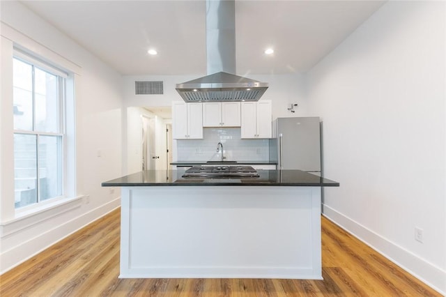 144 N Washington Ave Unit 102, Fayetteville, AR 72701 - kitchen with appliances with stainless steel finishes, visible vents, island range hood, white cabinets, and decorative backsplash