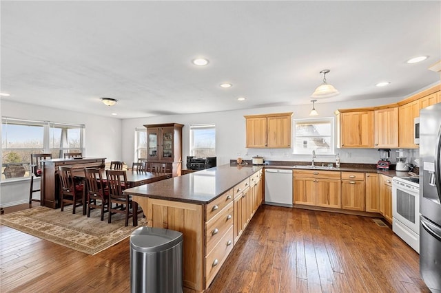 kitchen featuring white appliances, dark wood-style flooring, light brown cabinetry, a sink, and a peninsula