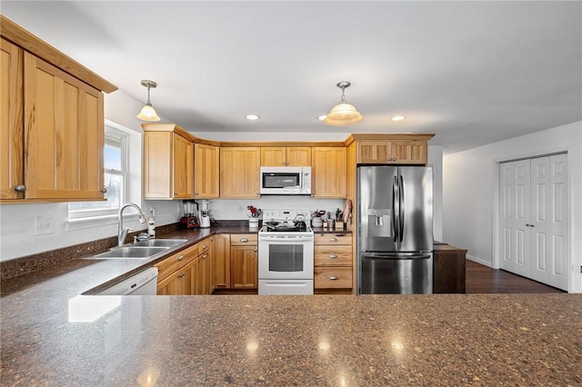 kitchen featuring a sink, pendant lighting, white appliances, recessed lighting, and dark stone counters