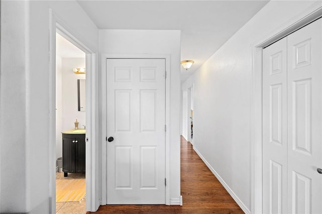 corridor featuring a sink, baseboards, and wood finished floors