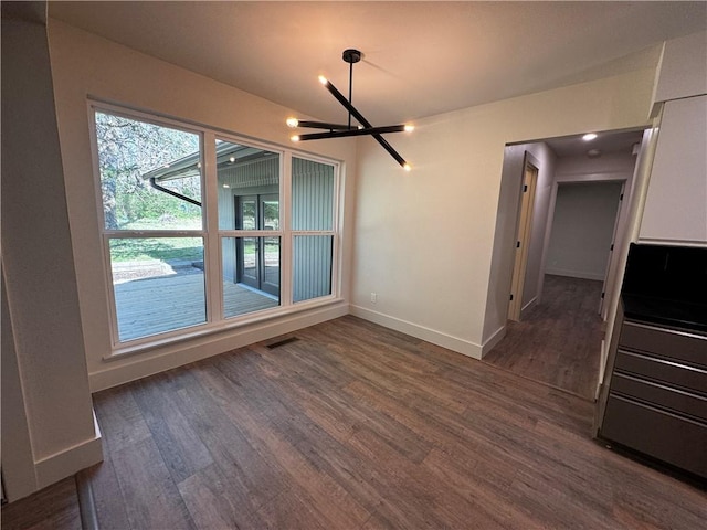 unfurnished dining area with dark wood-style floors, visible vents, and baseboards