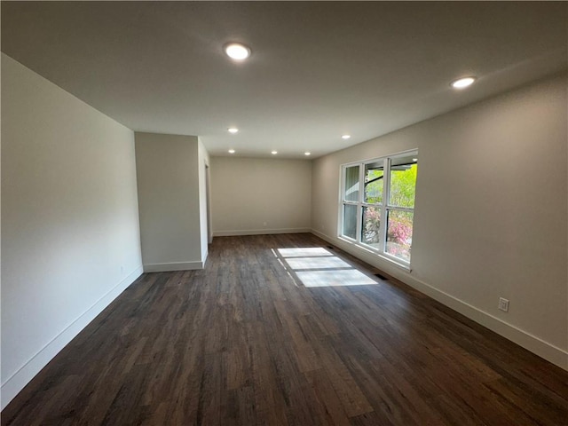 spare room with dark wood-style flooring, baseboards, and recessed lighting
