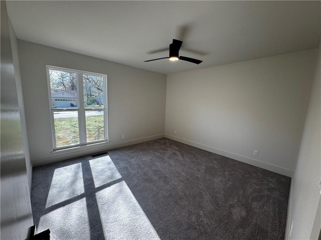 empty room with baseboards, visible vents, dark colored carpet, and ceiling fan
