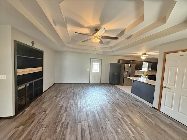 5 Arrowhead Ln, Clarksville, AR 72830 - unfurnished living room featuring a tray ceiling, a ceiling fan, light wood finished floors, and baseboards