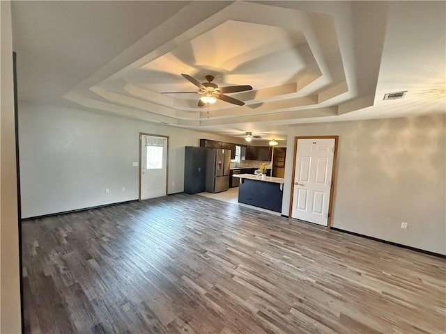 5 Arrowhead Ln, Clarksville, AR 72830 - unfurnished living room with a raised ceiling, a ceiling fan, light wood-type flooring, and baseboards