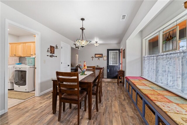 dining room featuring baseboards, washer / dryer, visible vents, a notable chandelier, and wood finished floors
