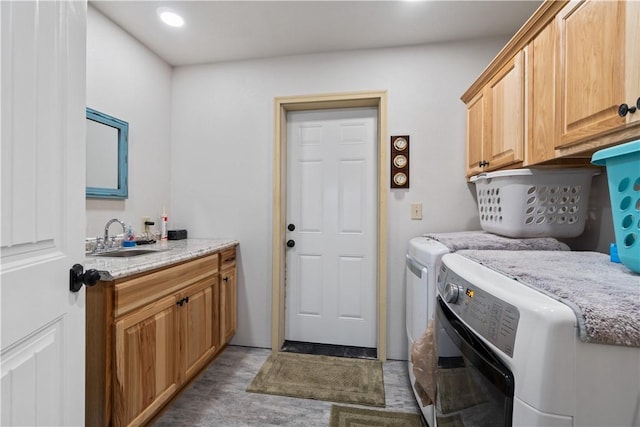 clothes washing area with a sink, cabinet space, and washer and dryer