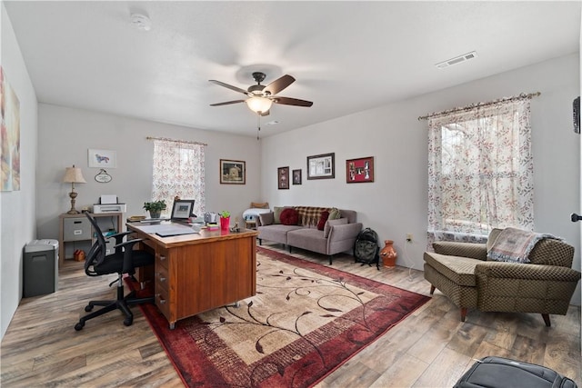 home office featuring visible vents, light wood-style floors, and a ceiling fan