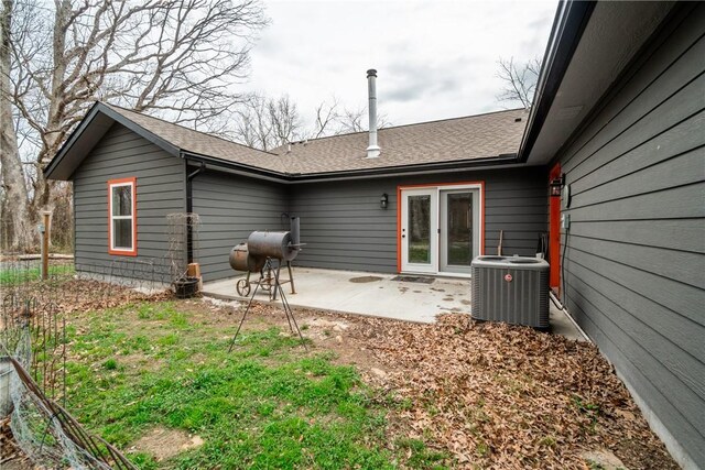 back of house with central AC unit, a shingled roof, and a patio area