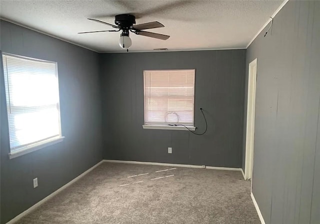 spare room featuring a textured ceiling, carpet flooring, and a ceiling fan