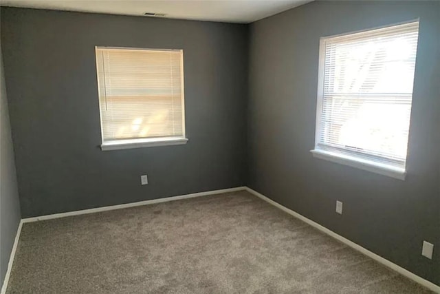 carpeted spare room featuring baseboards