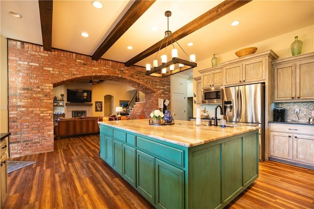 kitchen featuring open floor plan, a center island with sink, dark wood-type flooring, arched walkways, and appliances with stainless steel finishes
