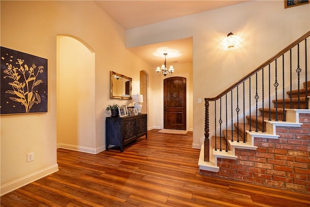 entryway with wood finished floors, baseboards, arched walkways, and stairs