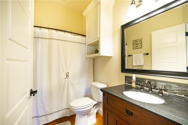 full bath featuring toilet, vanity, curtained shower, decorative backsplash, and baseboards