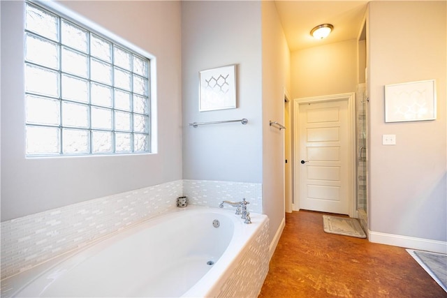 full bathroom featuring a bath, baseboards, and a stall shower