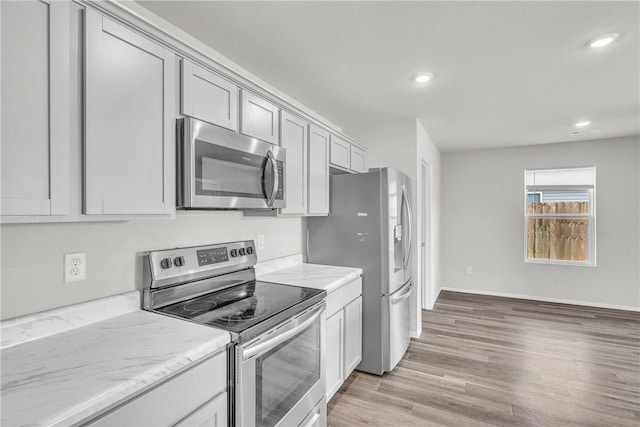 1405 Corsac St, Siloam Springs, AR 72761 - kitchen featuring stainless steel appliances, light wood-style floors, recessed lighting, light stone countertops, and baseboards