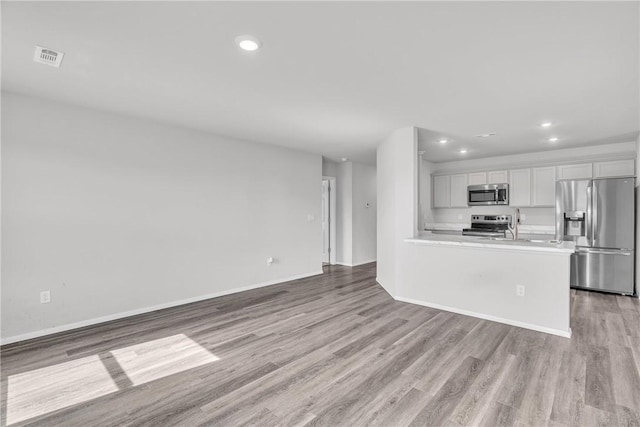 1405 Corsac St, Siloam Springs, AR 72761 - kitchen featuring appliances with stainless steel finishes, recessed lighting, light wood-style flooring, light countertops, and white cabinets