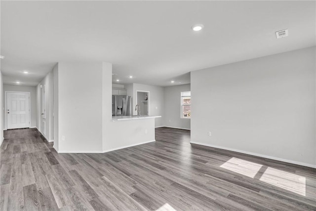 1405 Corsac St, Siloam Springs, AR 72761 - unfurnished living room with dark wood-type flooring, recessed lighting, baseboards, and a sink
