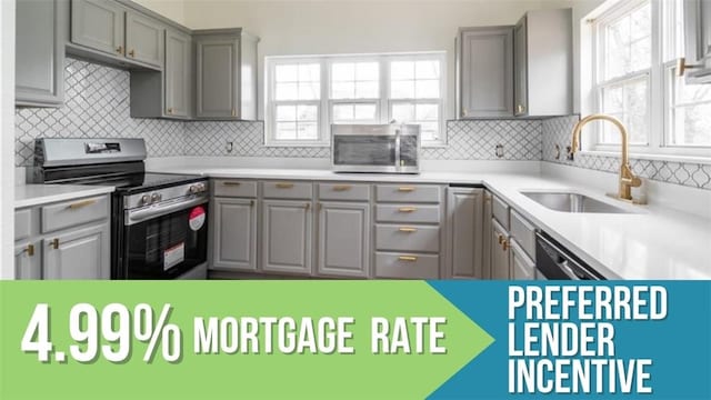 501 SW 2nd Ave, Gravette, AR 72736 - kitchen with stainless steel appliances, gray cabinetry, and healthy amount of natural light