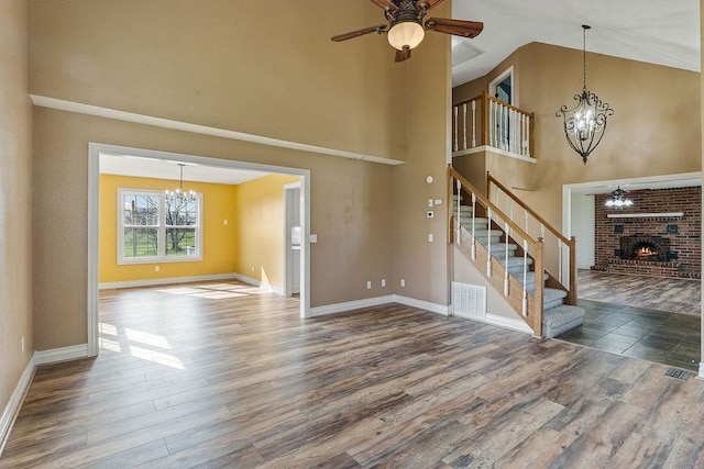 188 Lonestar Rd, Anderson, MO 64831 - unfurnished living room featuring a chandelier, stairway, ceiling fan, wood finished floors, and high vaulted ceiling