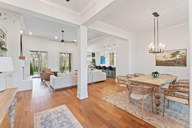 dining area featuring light wood-style flooring, crown molding, and ceiling fan with notable chandelier
