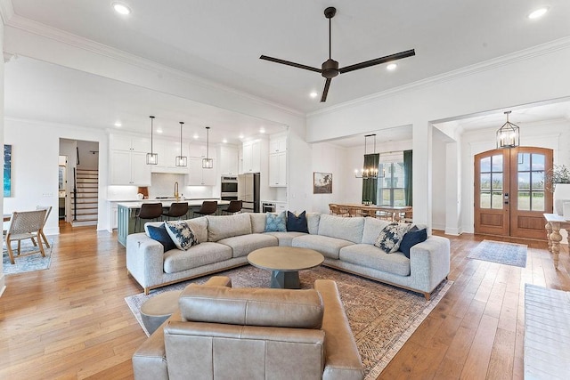 living area with ornamental molding, recessed lighting, french doors, light wood finished floors, and ceiling fan with notable chandelier