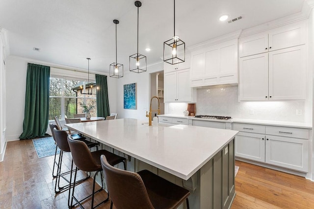 kitchen with visible vents, light countertops, a sink, and ornamental molding