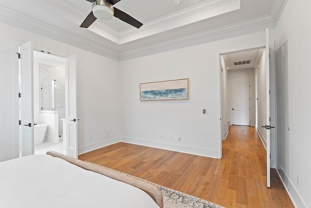 bedroom with baseboards, light wood-type flooring, crown molding, visible vents, and a tray ceiling