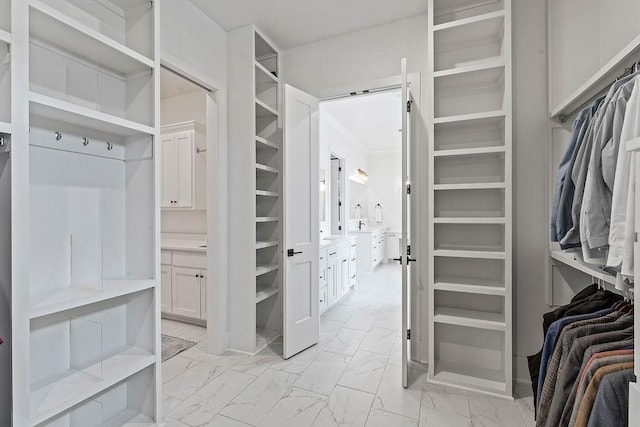 walk in closet featuring marble finish floor and a barn door