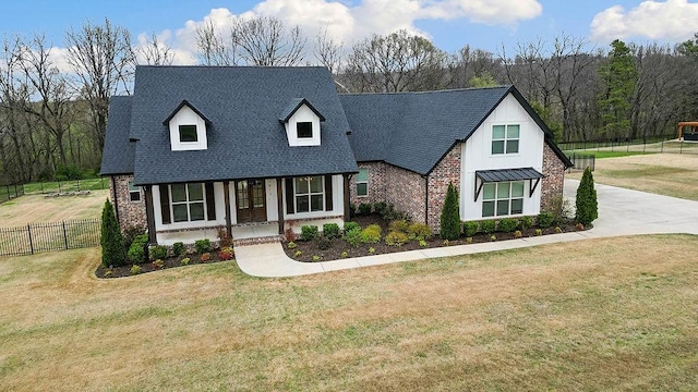 view of front of house featuring a shingled roof, fence, a front lawn, and brick siding