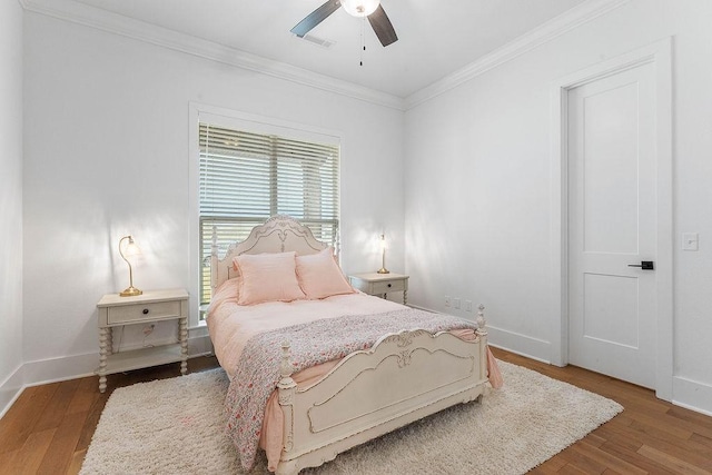 bedroom with crown molding, wood finished floors, and baseboards