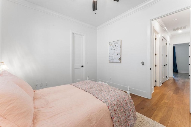 bedroom with crown molding, light wood finished floors, baseboards, and visible vents