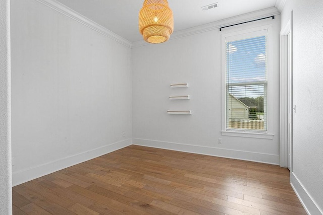 unfurnished room with ornamental molding, visible vents, baseboards, and wood-type flooring