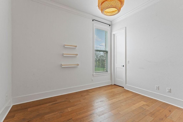 empty room featuring crown molding, wood-type flooring, and baseboards